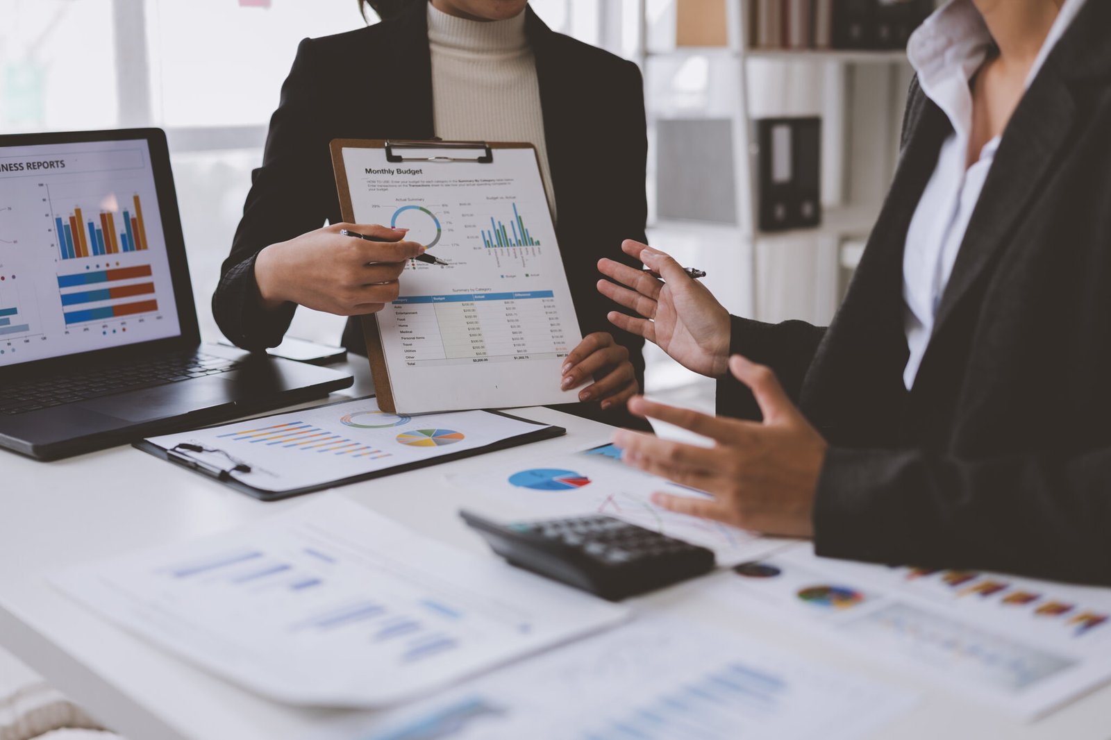 businesswomen analyzing financial reports and discussing monthly budget